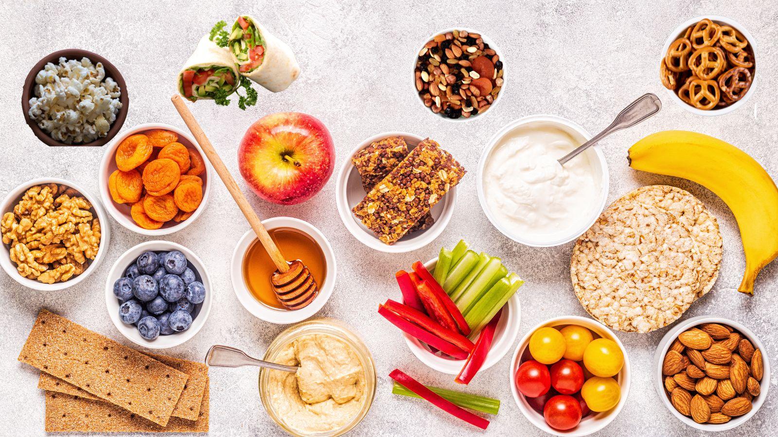 A collage of healthy snack ideas for kids including fruits, vegetables, nuts, pretzels, popcorn and trail mix.