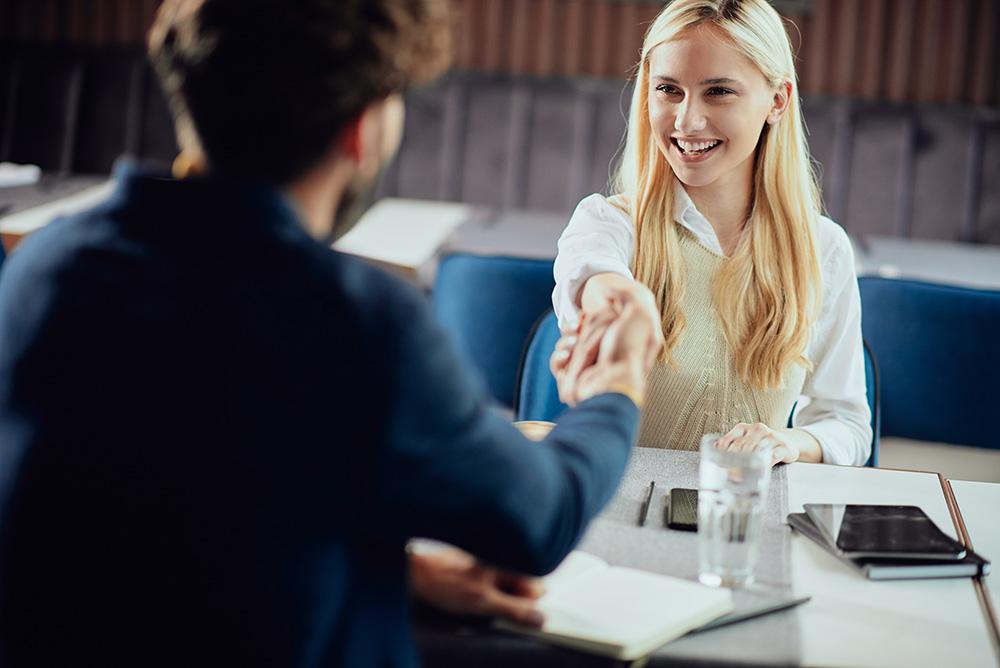 Two business partners shaking hands while sitting in coffee shop.