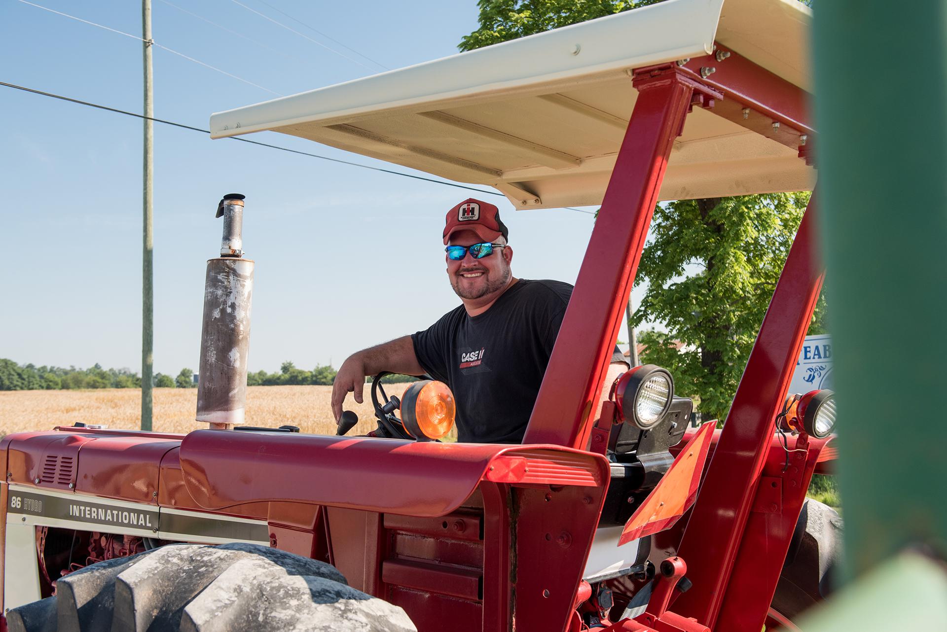 Farmer in the driver seat of a tractor turned around to smile at the camera