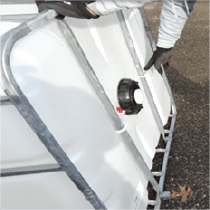 Person removing plastic rings from metal bars on an IBC