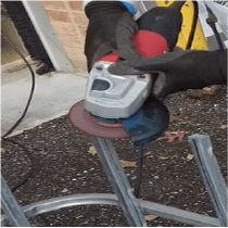 A person using a grinder to smooth the cut areas on the metal IBC cage.